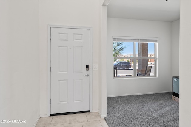 foyer entrance featuring light carpet, baseboards, and light tile patterned floors