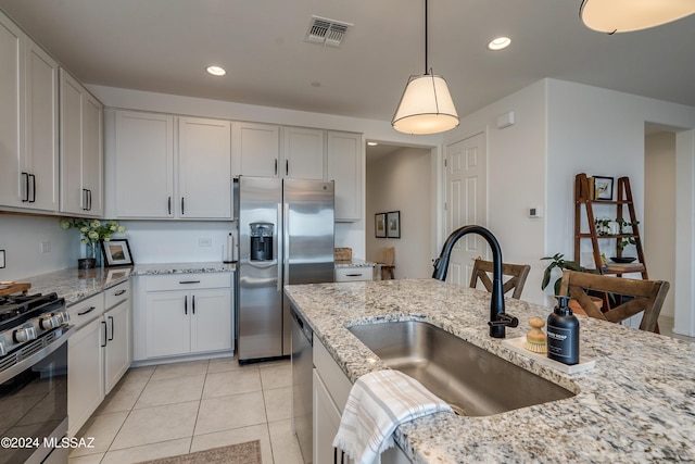 kitchen with sink, stainless steel appliances, white cabinetry, light tile patterned flooring, and pendant lighting