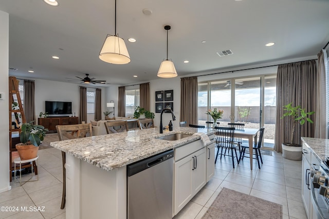 kitchen with hanging light fixtures, an island with sink, white cabinets, stainless steel dishwasher, and sink