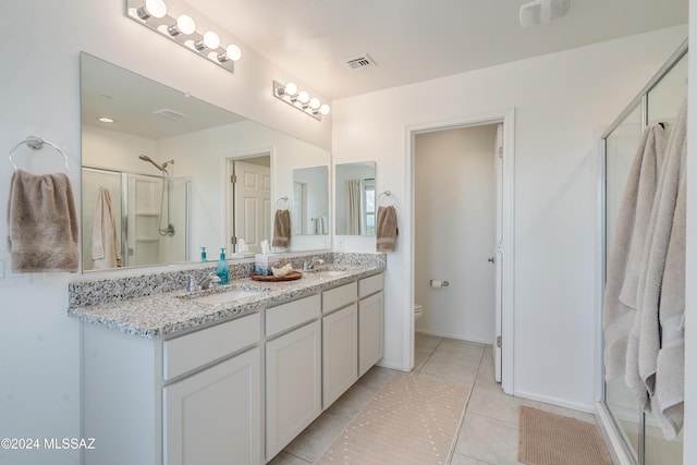 bathroom with toilet, tile patterned flooring, a shower with shower door, and vanity