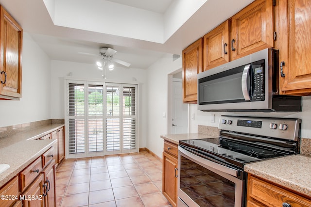 kitchen with ceiling fan, appliances with stainless steel finishes, light stone counters, and light tile patterned floors