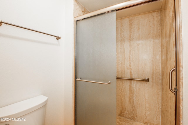 bathroom featuring a shower with shower door and toilet