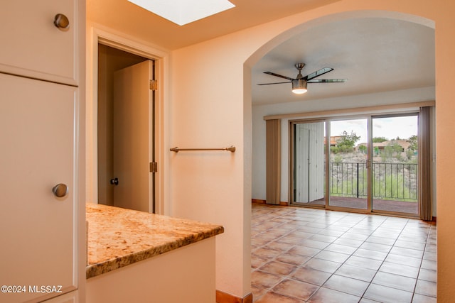 interior space with ceiling fan, a skylight, and light tile patterned floors