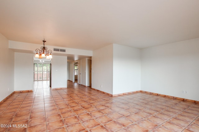 tiled spare room with an inviting chandelier