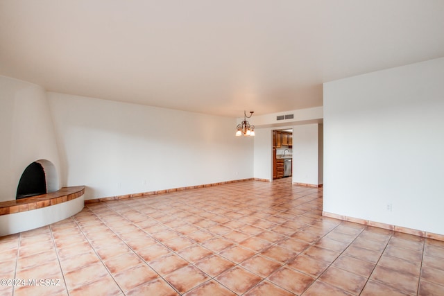 tiled spare room with a chandelier