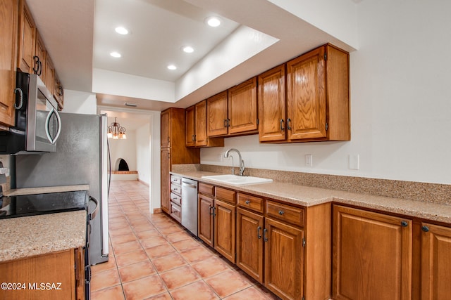 kitchen with appliances with stainless steel finishes, light stone countertops, light tile patterned floors, sink, and a chandelier