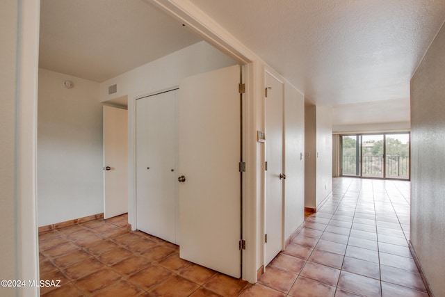 hallway featuring a textured ceiling and light tile patterned floors