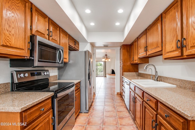 kitchen featuring light stone counters, an inviting chandelier, appliances with stainless steel finishes, and light tile patterned floors