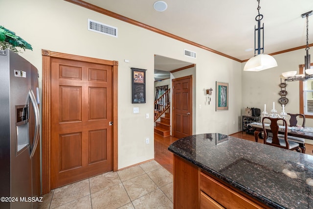 kitchen with dark stone countertops, crown molding, light hardwood / wood-style flooring, decorative light fixtures, and stainless steel fridge with ice dispenser