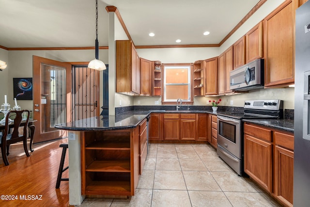 kitchen with light hardwood / wood-style flooring, decorative light fixtures, appliances with stainless steel finishes, dark stone counters, and ornamental molding