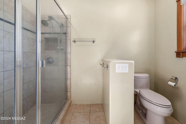 bathroom featuring tile patterned flooring, toilet, and walk in shower