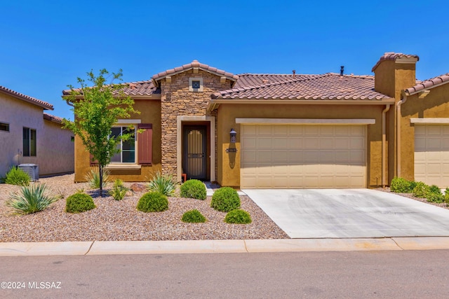 mediterranean / spanish house with a garage and central AC unit