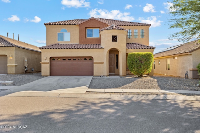 mediterranean / spanish-style home featuring stucco siding, a tiled roof, concrete driveway, and a garage