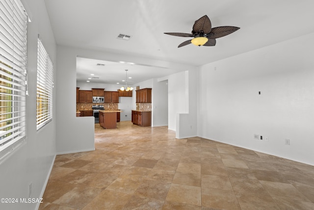 unfurnished living room featuring ceiling fan with notable chandelier