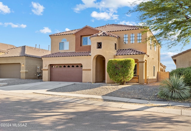 mediterranean / spanish-style house featuring stucco siding, driveway, a tile roof, fence, and a garage