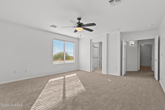 unfurnished bedroom featuring a walk in closet, ceiling fan, a closet, and light carpet