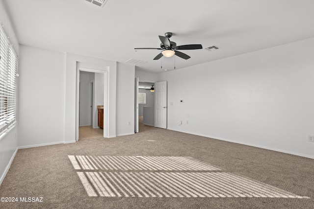 unfurnished bedroom featuring connected bathroom, light carpet, and ceiling fan