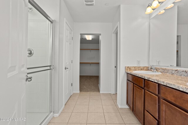 bathroom with a shower with door, vanity, and tile patterned floors