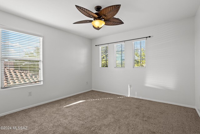 unfurnished room featuring plenty of natural light, ceiling fan, and carpet flooring