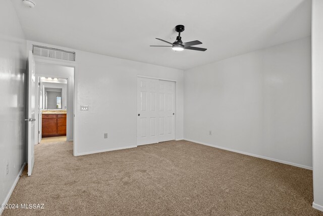 unfurnished bedroom with light colored carpet, ceiling fan, and a closet