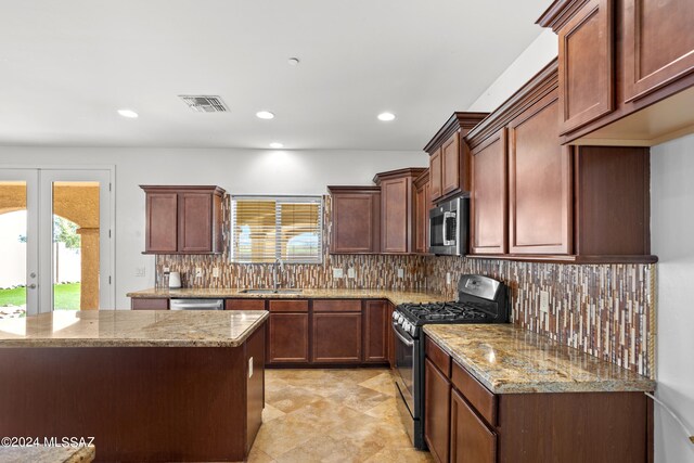 kitchen with appliances with stainless steel finishes, a wealth of natural light, light stone countertops, and sink