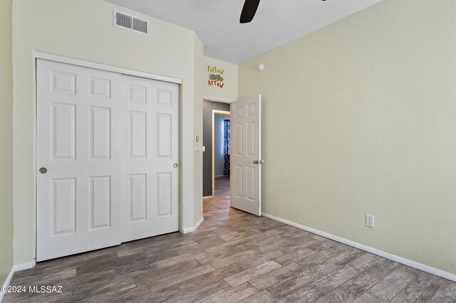 unfurnished bedroom with wood-type flooring, a closet, and ceiling fan