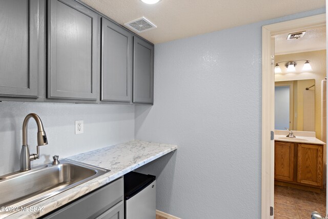 kitchen with a textured ceiling, sink, gray cabinets, and tile patterned floors