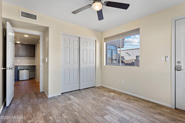 unfurnished bedroom with ceiling fan, a closet, and light hardwood / wood-style floors