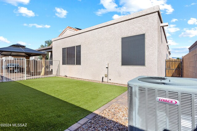 rear view of house with a patio, central AC unit, a gazebo, and a yard