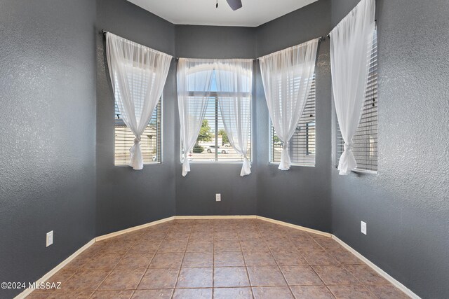 tiled empty room featuring ceiling fan