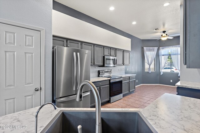 kitchen featuring sink, gray cabinetry, stainless steel appliances, light tile patterned floors, and ceiling fan