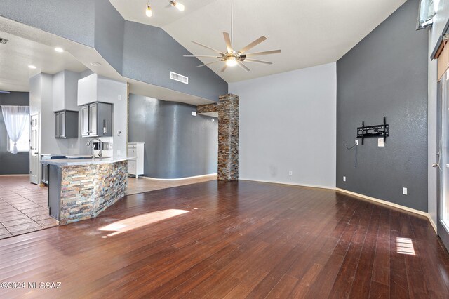 unfurnished living room featuring high vaulted ceiling, ceiling fan, and dark wood-type flooring