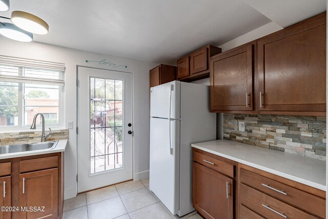 kitchen with tasteful backsplash, sink, light tile patterned floors, and white refrigerator