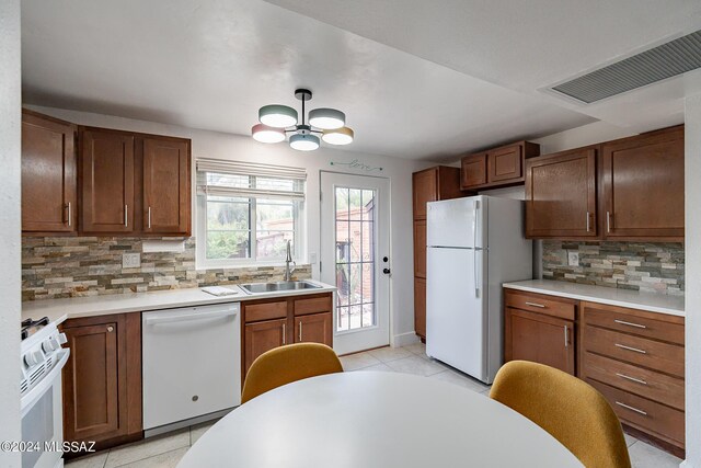 kitchen featuring backsplash, white appliances, an inviting chandelier, and sink