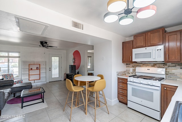 kitchen featuring light tile patterned flooring, ceiling fan with notable chandelier, tasteful backsplash, and white appliances