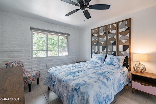 tiled bedroom with ceiling fan and brick wall