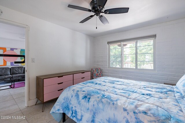 tiled bedroom with ceiling fan and brick wall