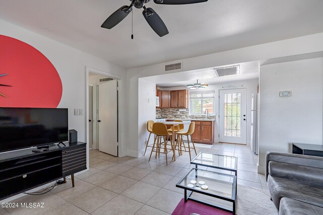 tiled living room featuring ceiling fan and sink