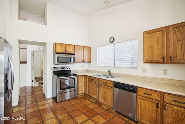 kitchen with stainless steel appliances, sink, and high vaulted ceiling