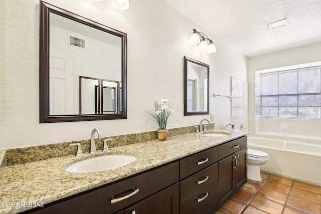 bathroom with a bathtub, vanity, a textured ceiling, tile patterned flooring, and toilet