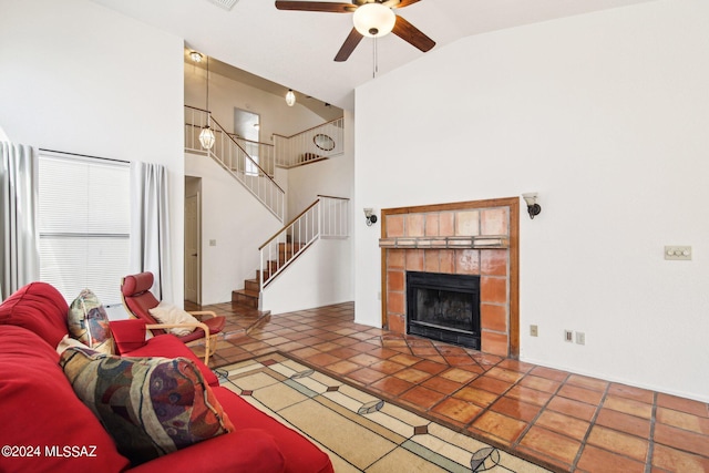 living room with high vaulted ceiling, ceiling fan, a tile fireplace, and tile patterned floors