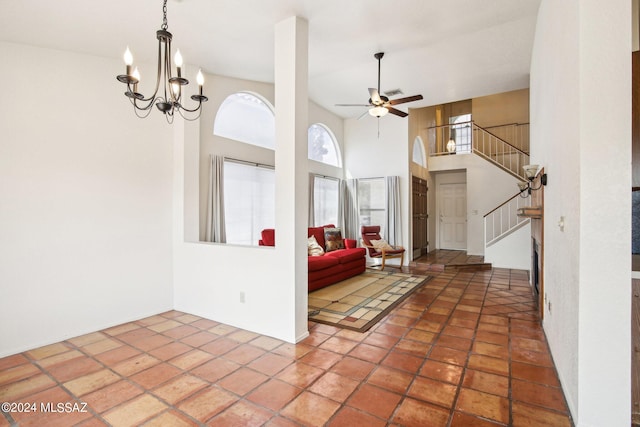 entrance foyer with ceiling fan with notable chandelier, a towering ceiling, and tile patterned floors