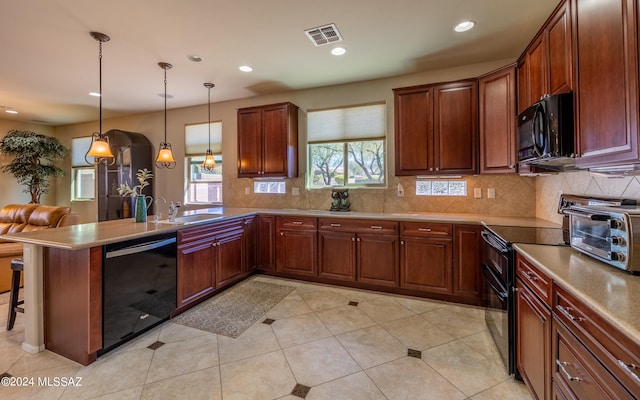 kitchen featuring pendant lighting, black appliances, backsplash, a breakfast bar, and kitchen peninsula