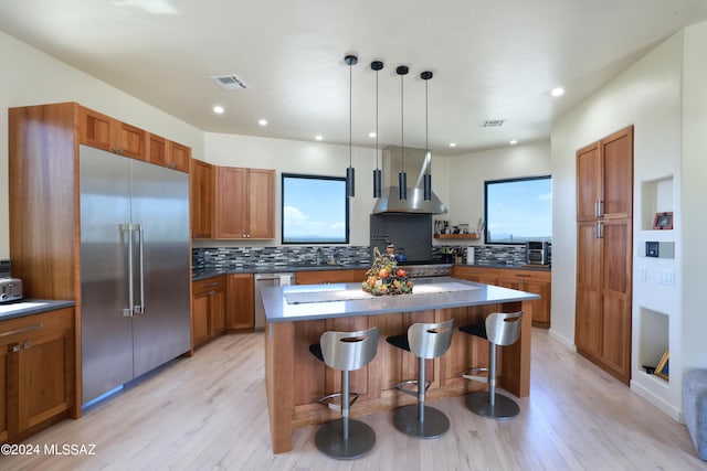 kitchen with plenty of natural light, light hardwood / wood-style flooring, stainless steel appliances, and a breakfast bar