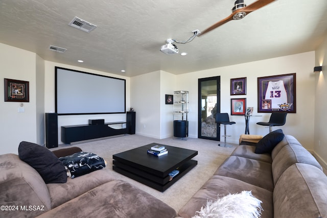 home theater room with light colored carpet and a textured ceiling