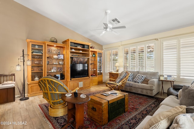 living room featuring ceiling fan, light wood-type flooring, and vaulted ceiling