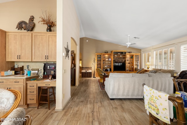 living room with light wood-type flooring, vaulted ceiling, and ceiling fan