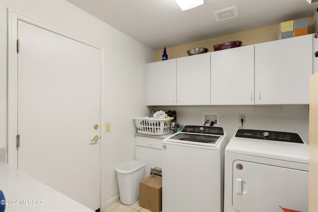 washroom featuring cabinets, light tile patterned floors, and washer and clothes dryer