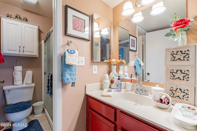 bathroom with vanity, walk in shower, a textured ceiling, toilet, and tile patterned floors