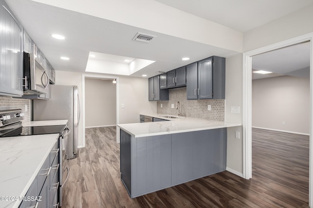 kitchen featuring appliances with stainless steel finishes, sink, gray cabinets, kitchen peninsula, and dark wood-type flooring